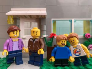 A mother, father and two children smiling outside their home.