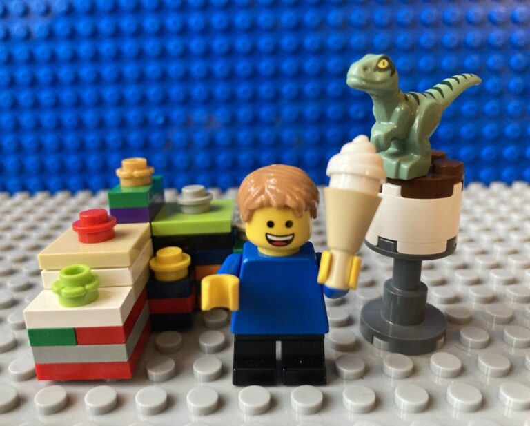 child eating ice-cream surrounded by presents and a birthday cake with dinosaur on top.