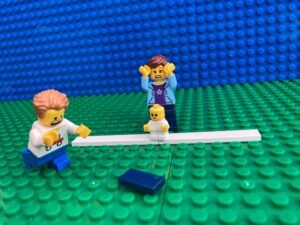 Child trying to reach the beanbag they have dropped in school sports day race