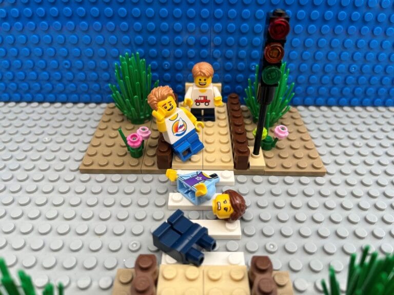 lego Child looking smug while lego Mum lays across the road in pieces.