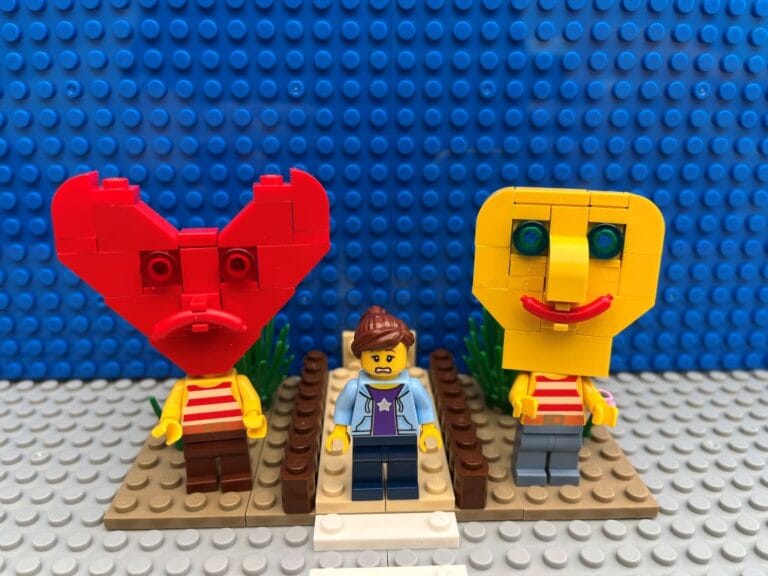 Mum standing at the roadside having to make a decision about child crossing the road. Heart character and Head characters are standing next to her.