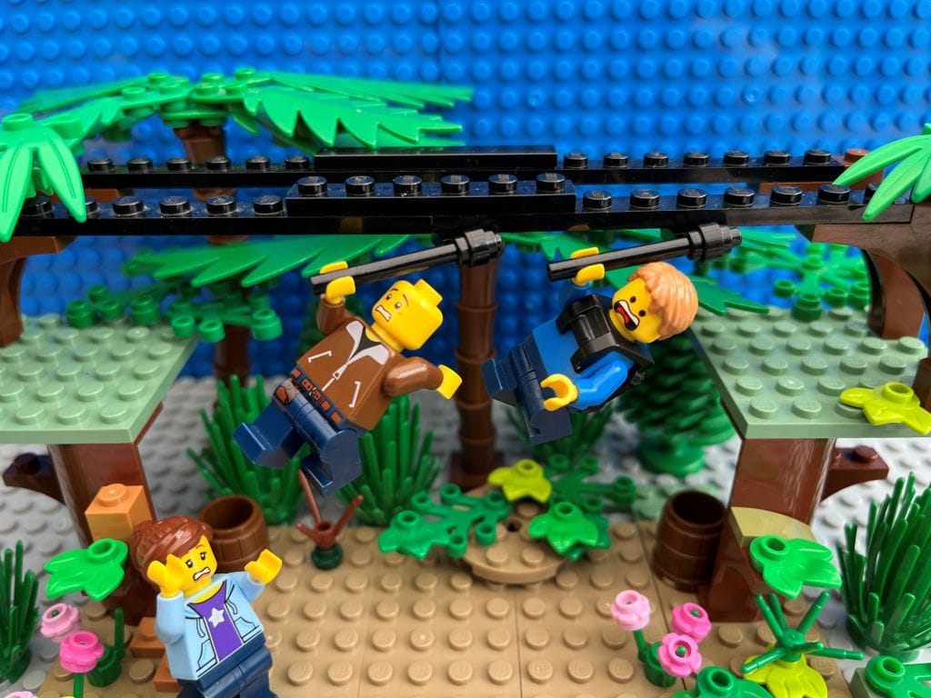 Dad and child both flying down a zip-line together looking terrified