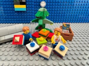 Children sitting by a Christmas tree holding some brightly coloured Christmas presents