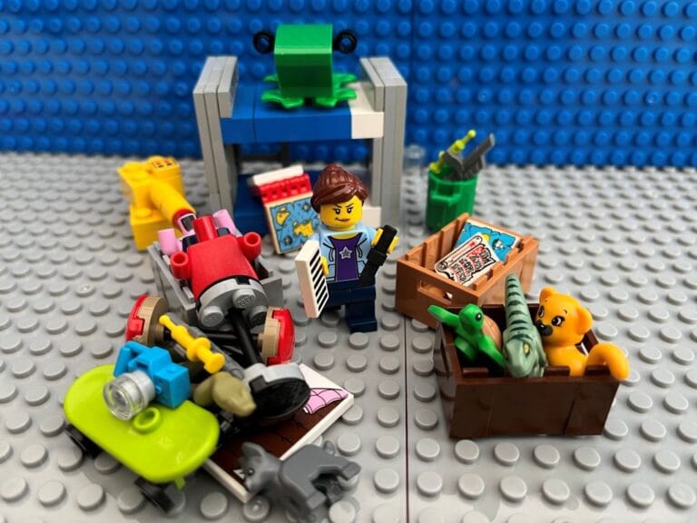 Mum having a January clear out with the children's toys, putting a pile of things including a green skateboard into brown boxes