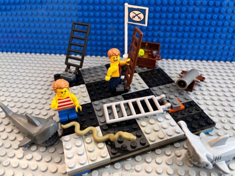 Two children playing on a giant snakes and ladders board game