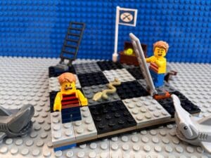 One child looking horrified while another happily climbs the ladder in a snakes and ladders giant board game