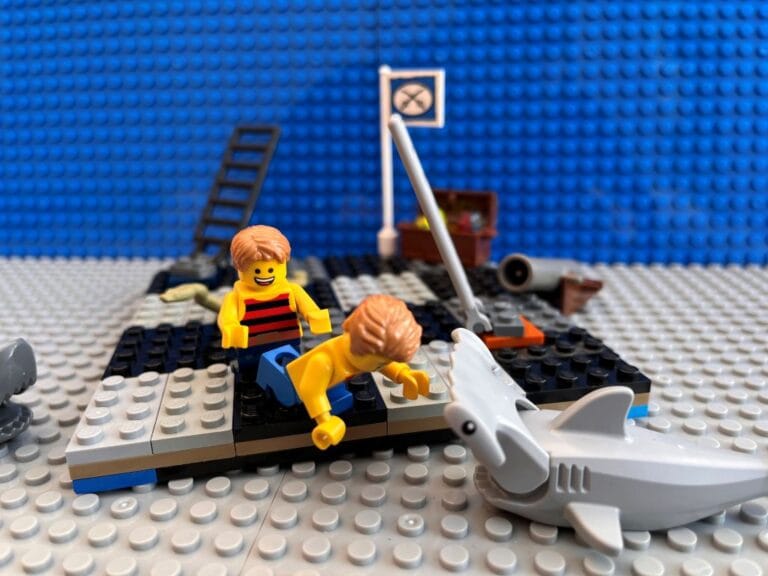 Younger child pushing oldest child towards the toy shark off the board game