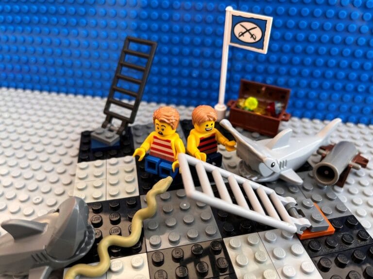 Two cross children sitting on a giant snakes and ladders board game