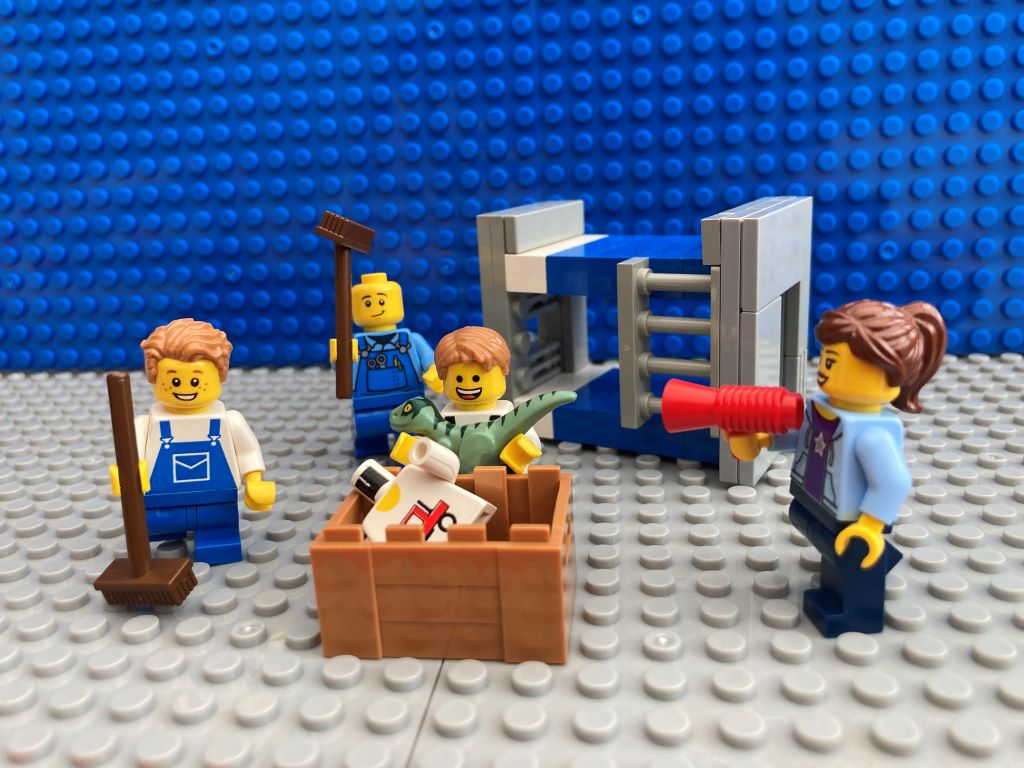 Family doing easy everyday chores together. In this image they are all tidying up the children's bedroom by putting toys in a box