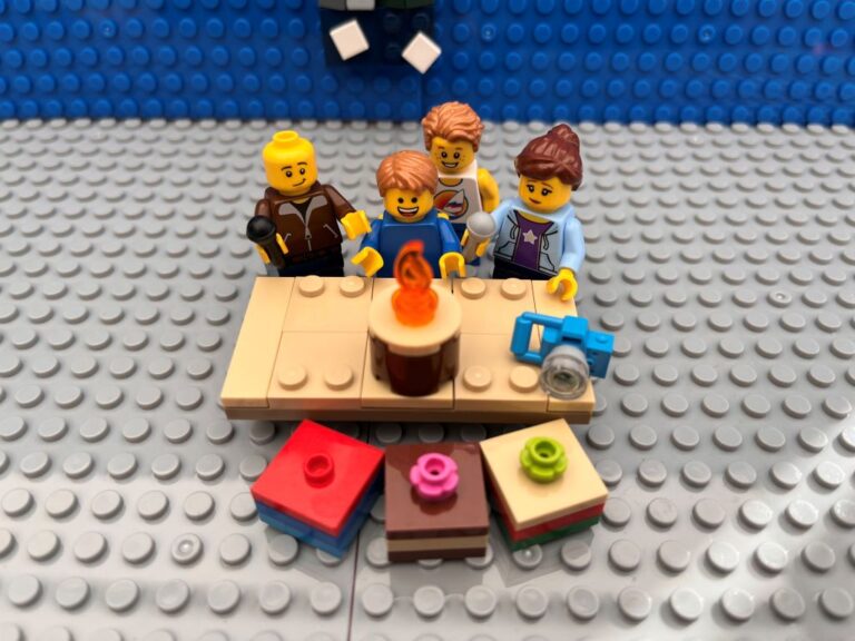 Child blowing out the candles on a birthday cake while family stand around him singing happy birthday