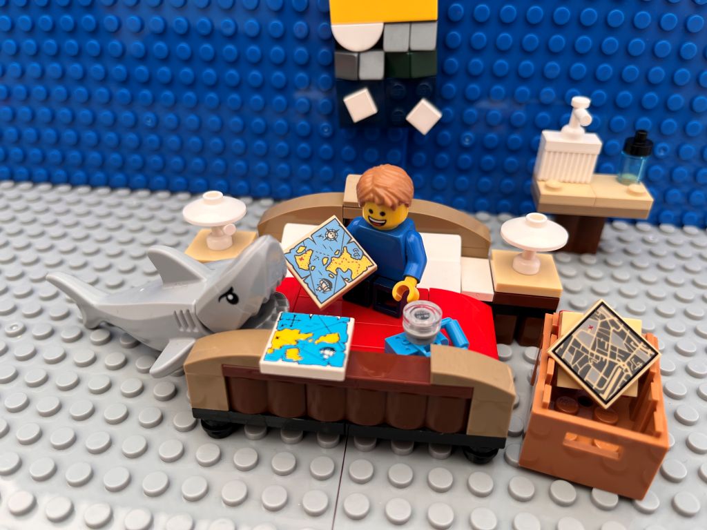 Child sitting on a bed with lots of maps trying to decide on a great birthday trip idea for his 10th birthday