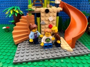 Child sat with a cross expression on his face at the bottom of the climbing frame with his worried parents crowding around him